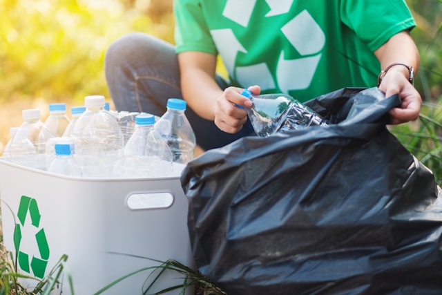 Kobieta zbiera butelki plastikowe do kosza na odpady plastikowe