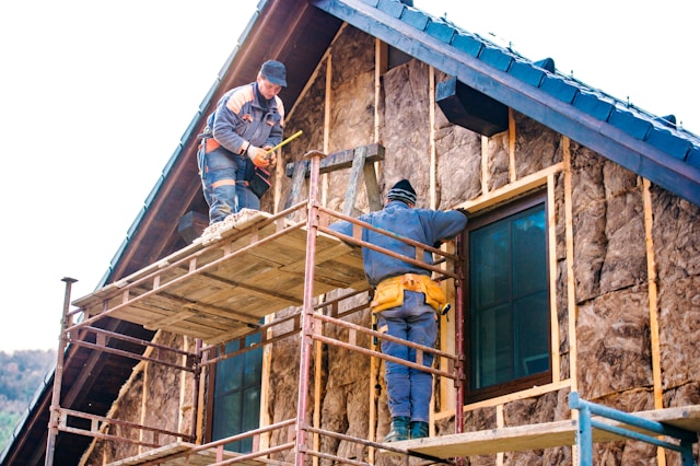 dwóch mężczyzn kładących wełnę mineralną na elewacje