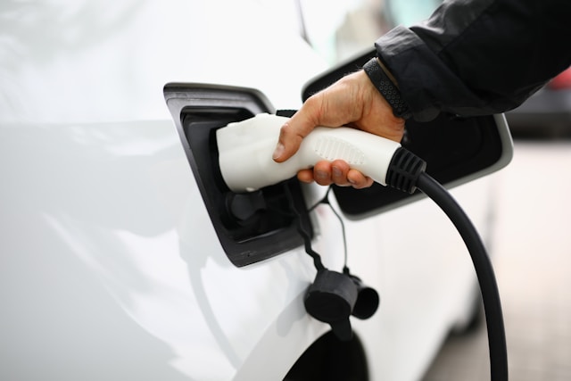 mężczyzna ładuje biały samochód elektryczny widok od pilota ładowania