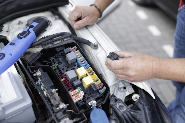 mężczyzna sprawdza elektrykę akumlatora w samochodzie